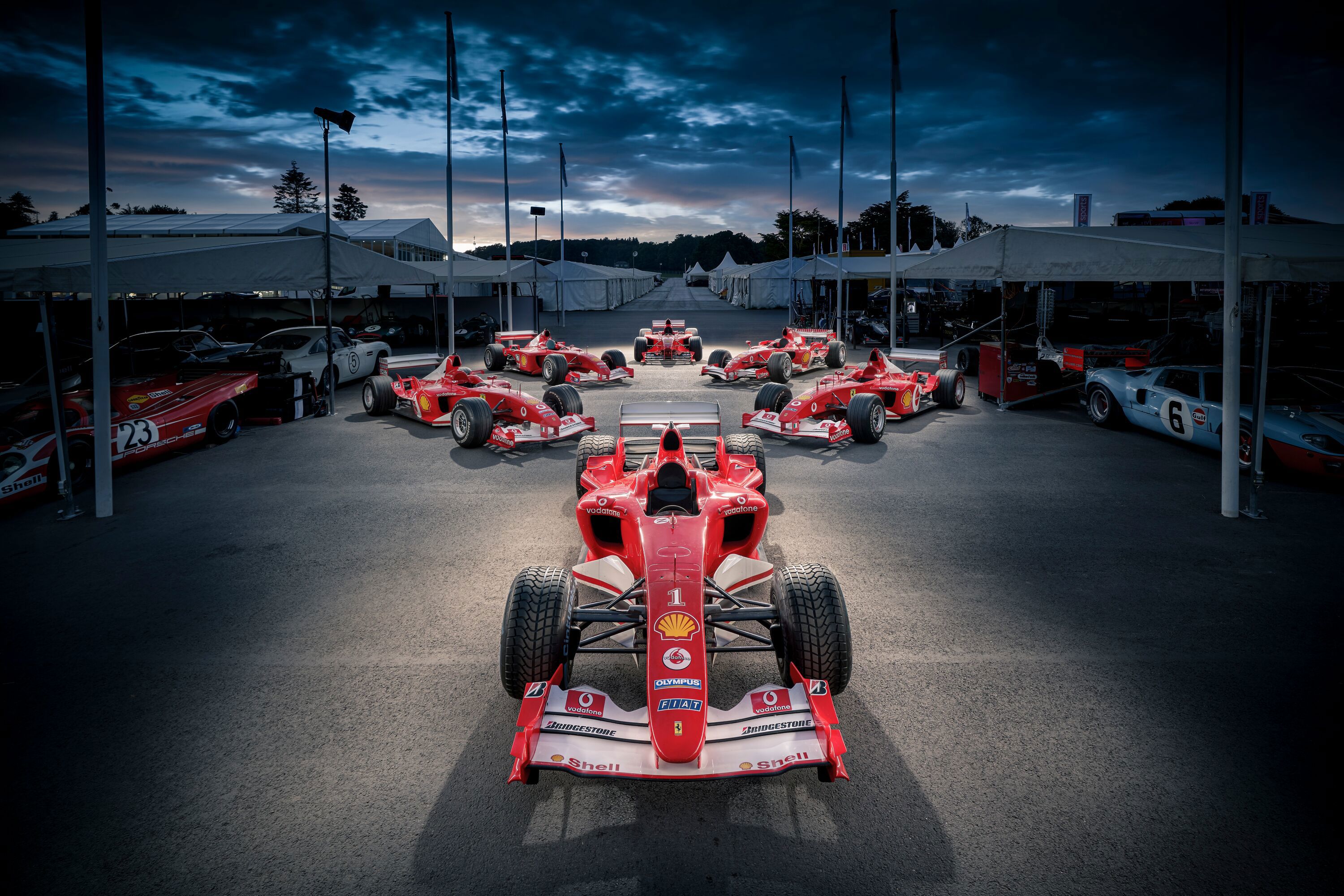 Six F1 Ferraris that were driven by Michael Schumacher photographed in the Assembly Area at FoS2019. The largest collection of cars raced by Michael Schumacher have been brought together at this year’s Goodwood Festival of Speed presented by Mastercard. .Leading car photographer Nigel Harniman used a technique called light painting  to create the stunning image..Clockwise from front:.Ferrari F2004 – The Ferrari era of dominance ended with its most awe-inspiring season; the team pulling out all the stops to create the ultimate car of the V10 era and giving Schumacher 13 wins from 18 starts...Ferrari F2003-GA – The prancing horse stumbled in 2003, its performance advantage over Williams-BMW reversed and McLaren’s rising star Kimi Räikkönen driving beautifully – but Ferrari’s teamwork and Schumacher’s peerless racecraft prevailed...Ferrari F2001 – Ferrari and Schumacher took their domination up a notch in 2001, with the German scoring more points than McLaren’s David Coulthard (second) and team-mate Rubens Barrichello (third) combined...Ferrari F399 was the car with which the Ferrari team competed in the 1999 Formula One season. Ferrari won their ninth Constructors' title, and their first since the 1983 season, paving the way for the Michael Schumacher era of Ferrari dominance beginning in 2000..Ferrari 248 The 248 was driven in 2006 by Michael Schumacher and Felipe Massa. The 248 was.generally not as fast as the Renault R26 in the first half of the season, and suffered from engine reliability issues throughout the season. Despite that the 248 won 9 races and took 7 pole positions, and finished in second place in both the Drivers' and Constructors' World Championships...Ferrari F2002 – This car redefined Formula 1 design with its unique lowline aerodynamics, seamless transmission and on-the-limit packaging brought Ferrari 15 wins (of which 10 were 1-2 finishes) from 17 races.