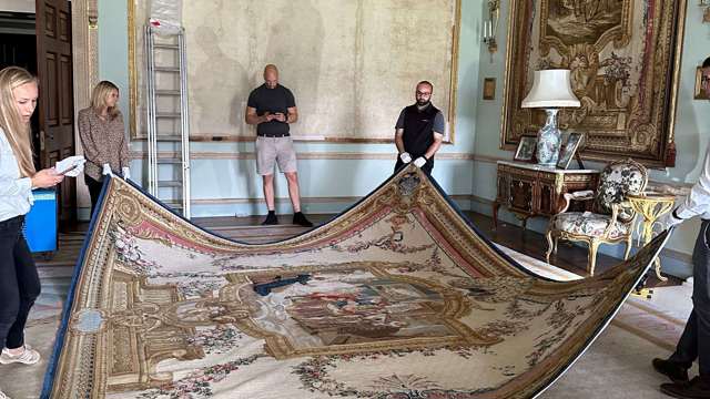 The Salvage Team handle the tapestry before turning it over to roll up.